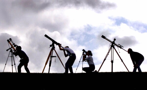FILE - Members of the British Astronomers Association prepare their telescopes at their campsite near Truro, England, on Tuesday, Aug. 10, 1999, preparing for a total solar eclipse the next day. (AP Photo/Dave Caulkin, File)